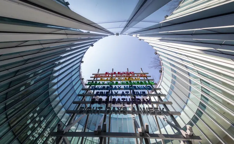 Futuristic glass building with colorful signage and modern steel structure.
