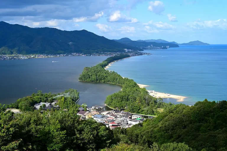 Stunning aerial view of Amanohashidate sandbar with vibrant greenery and blue waters in Japan.