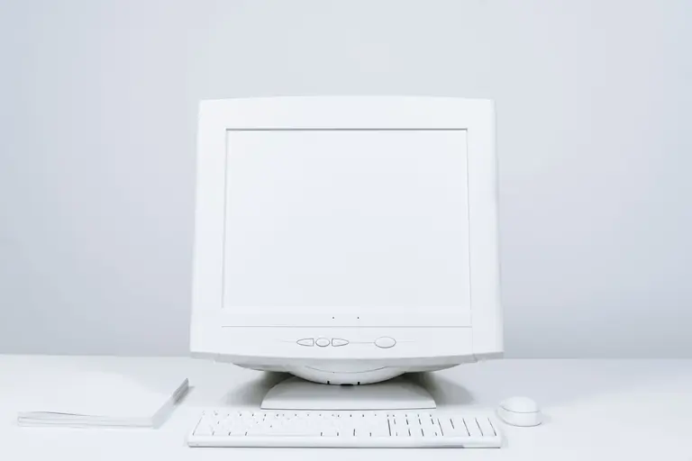 A minimalist white computer setup including monitor, keyboard, and mouse on desktop.