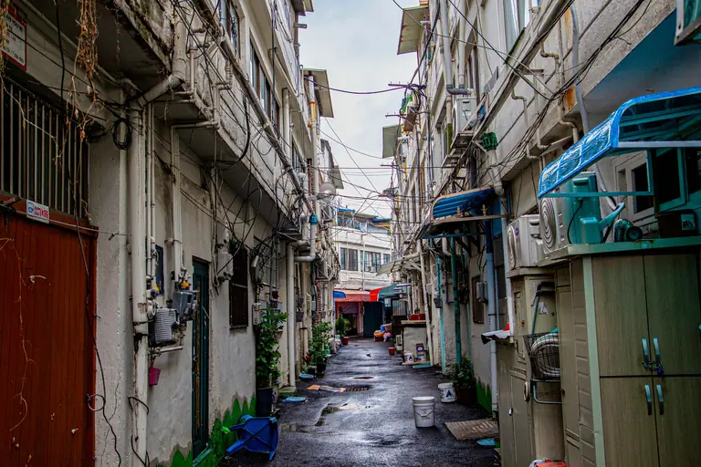 A narrow urban alley in Incheon with high-rise buildings and wires overhead, capturing a typical Korean cityscape.
