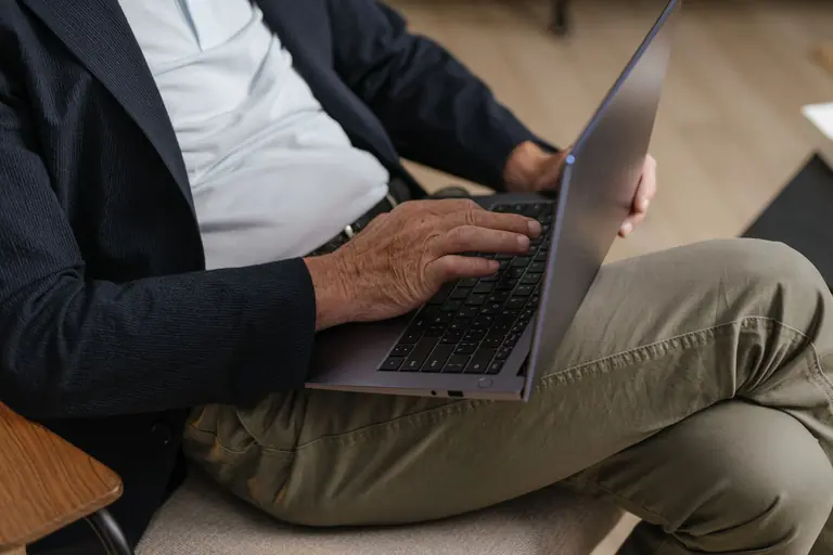 Adult working on a laptop while sitting comfortably indoors, focused on a task.