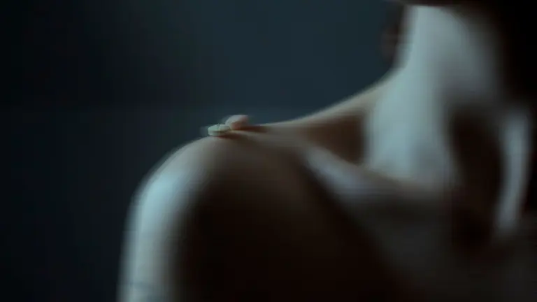 Blurry artistic image of tablets on a person's shoulder, emphasizing mood.