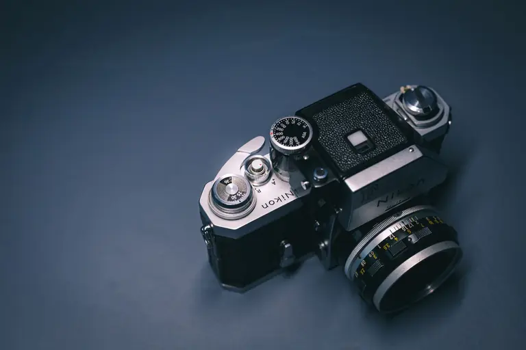 Detailed view of a classic Nikon film camera showcasing its mechanical features on a textured backdrop.